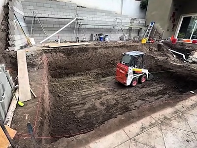 Excavated pool footprint with a skid loader in a La Verne backyard
