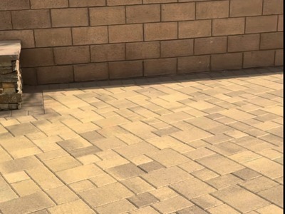 Multi-tone pavers laid against a custom stone wall in a Fontana backyard