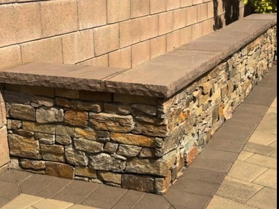 Close-up of stacked stone veneer and a wide flagstone cap on a Fontana seat wall